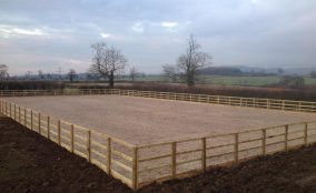 Newly completed riding arena surrounded by post and rail fencing