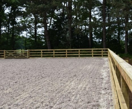 Sand Fibre Equestrian Riding Arena Located In North Yorkshire With Post & Raill Fence Surrounded By Trees