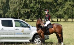 Rider on horse next to Hymas Arenas branded pickup