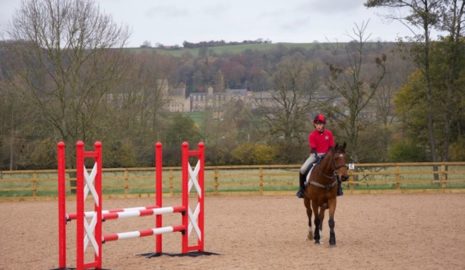 horse and rider in equine arena with Ampleforth college in the background